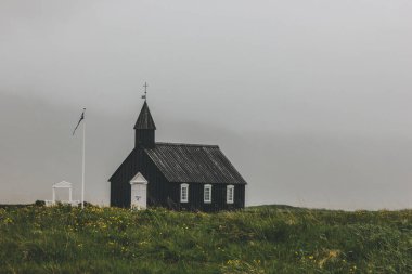 dramatic shot of Budir church on green field at Snaefellsnes, Iceland clipart