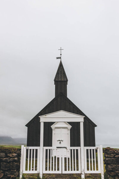 scenic shot of Budir church behind white wooden gate at Snaefellsnes, Iceland