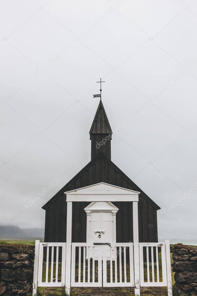 scenic shot of Budir church behind white wooden gate at Snaefellsnes, Iceland