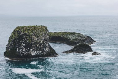 Arnarstapi, İzlanda'daki mavi okyanus bulutlu gün rock dramatik atış