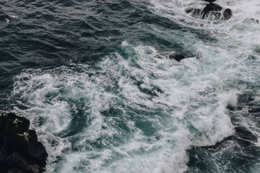 dramatic shot of foamy ocean waves crashing on rocks for background clipart