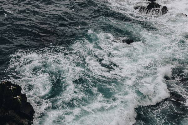 dramatic shot of foamy ocean waves crashing on rocks for background