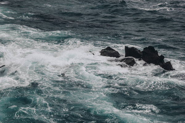 dramatic shot of blue ocean waves crashing on rocks for background