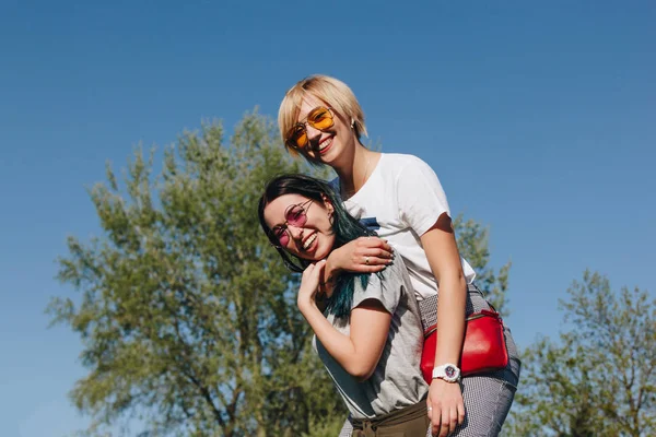 Vista inferior de las mujeres jóvenes felices abrazándose delante del cielo azul - foto de stock