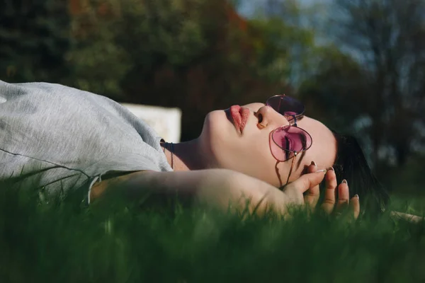 Beautiful young woman relaxing on grass in park — Stock Photo