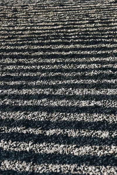 Close-up shot of pebbles on ground with straight shadow lines — Stock Photo