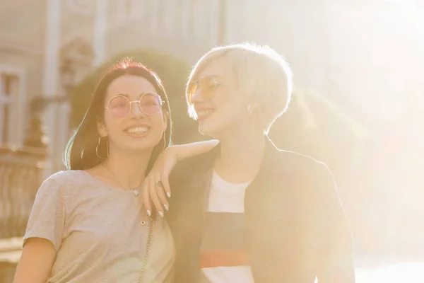Felices mujeres jóvenes con estilo en la ciudad europea en la puesta del sol - foto de stock