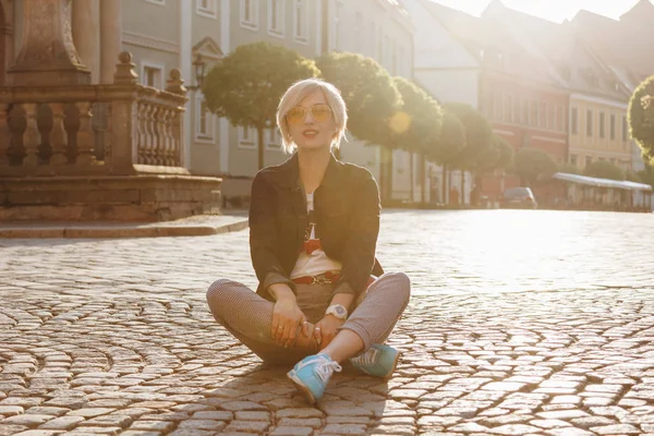 Hermosa joven sentada en adoquines en la calle wroclaw, Polonia - foto de stock