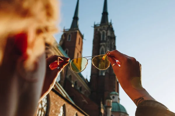 Cropped shot of woman holding stylish sunglasses and looking through at wroclaw cathedral — Stock Photo