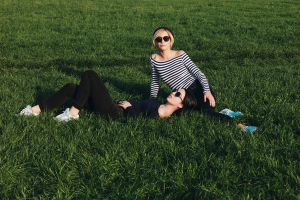Attractive young women relaxing on green grass in park — Stock Photo