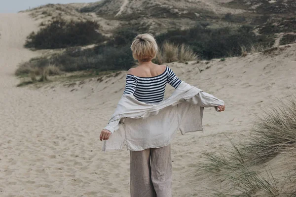 Rear view of young woman in stylish clothes on sand dune — Stock Photo