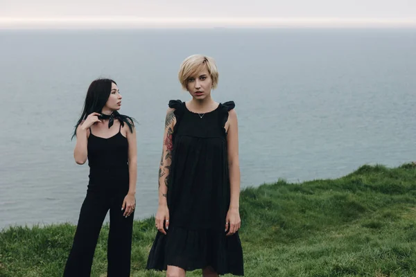 Belles jeunes femmes sur prairie verte en face de l'océan par temps nuageux — Photo de stock