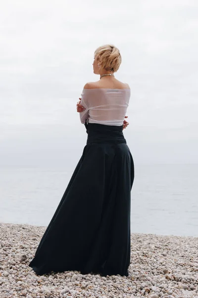 Vista posteriore di ragazza alla moda in posa sulla riva vicino al mare, Etretat, Normandia, Francia — Foto stock