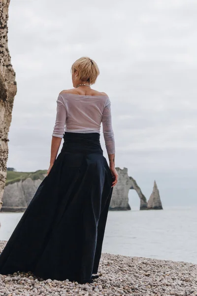 Rear view of fashionable elegant girl on shore near cliffs and sea, Etretat, Normandy, France — Stock Photo