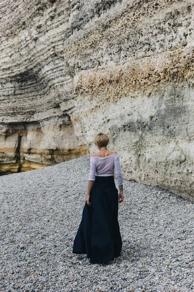 Vista posteriore di elegante ragazza a piedi sulla riva vicino scogliera, Etretat, Normandia, Francia — Foto stock