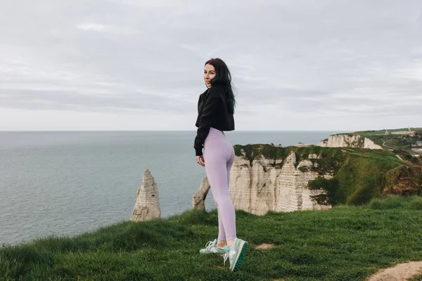 Deportista en ropa deportiva elegante posando en el acantilado, Etretat, Francia - foto de stock