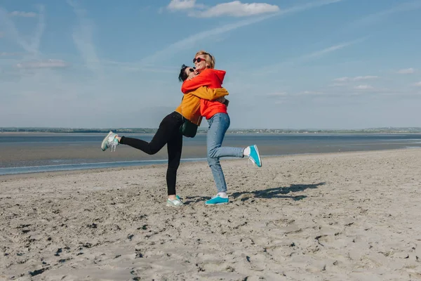 Happy friends hugging on sandy beach, Saint michaels mount, Normandia, França — Fotografia de Stock