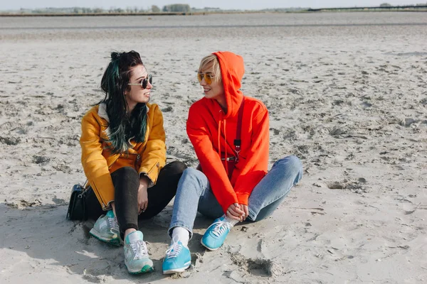 Happy female tourists sitting on sandy beach, Saint michaels mount, Normandia, França — Fotografia de Stock