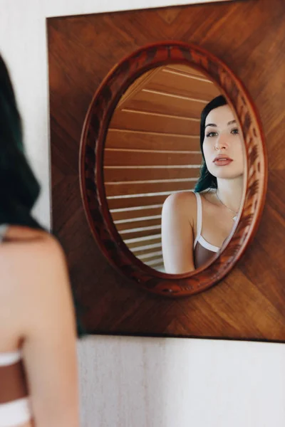 Schöne junge Frau in Unterwäsche, die in den Spiegel schaut — Stockfoto