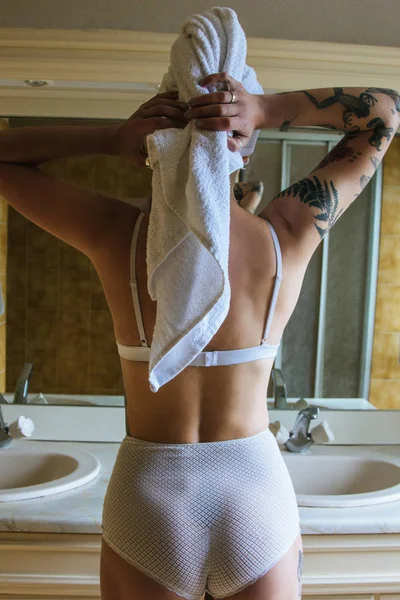 Vista posteriore della ragazza in lingerie e asciugamano guardando specchio in bagno — Foto stock