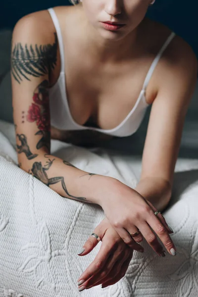 Cropped shot of sexy tattooed girl in bra lying on bed — Stock Photo