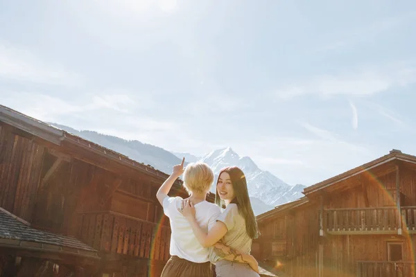 Vista trasera de las novias jóvenes abrazando y mirando hermosas montañas, mont blanc, alpes - foto de stock