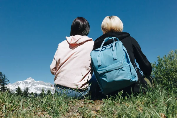 Vue arrière de jeunes voyageuses reposant sur l'herbe dans les montagnes, le mont blanc, les Alpes — Photo de stock