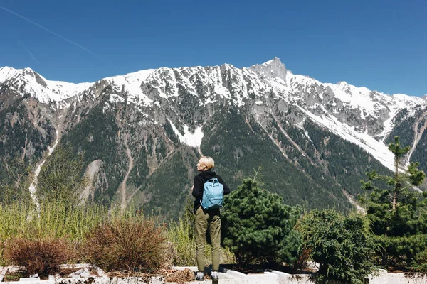 Вид сзади молодой женщины с рюкзаком, стоящей в величественных заснеженных горах, Монблан, Альпы — стоковое фото