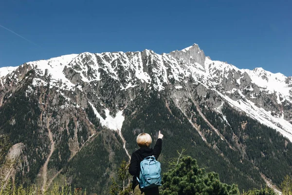 Vista trasera de la joven con la mochila apuntando con el dedo a las majestuosas montañas nevadas, mont blanc, alpes - foto de stock