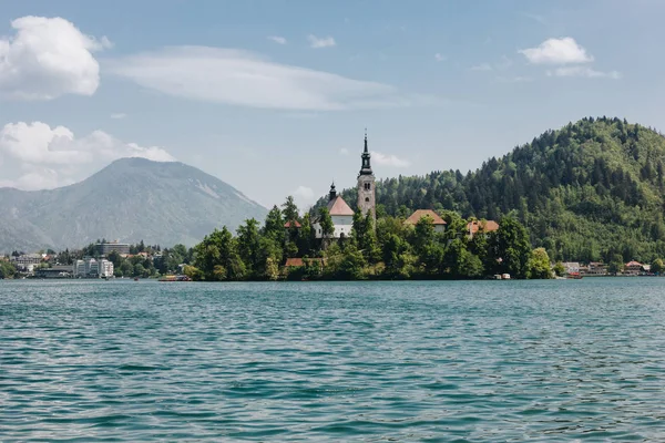 Architettura antica e alberi verdi in riva al lago di montagna panoramica, sanguinato, slovenia — Foto stock