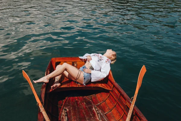 Vue grand angle de la jeune femme se détendre en bateau en bois sur le lac — Photo de stock