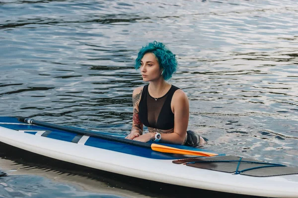 Bela jovem mulher com cabelo azul na água com placa de sup — Fotografia de Stock