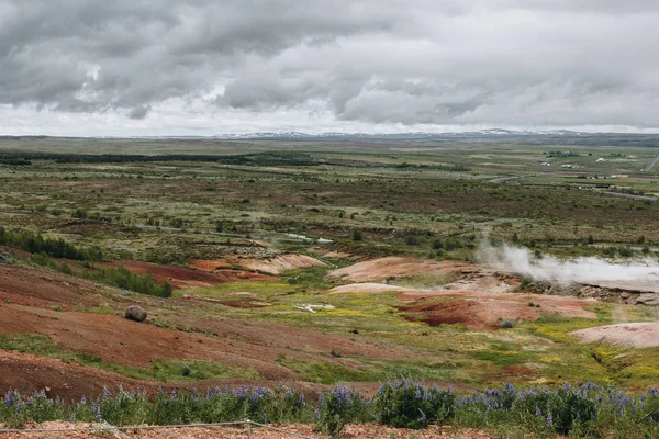 Vista panorámica del paisaje con respiraderos volcánicos bajo el cielo nublado en el valle de Haukadalur en Islandia — Stock Photo