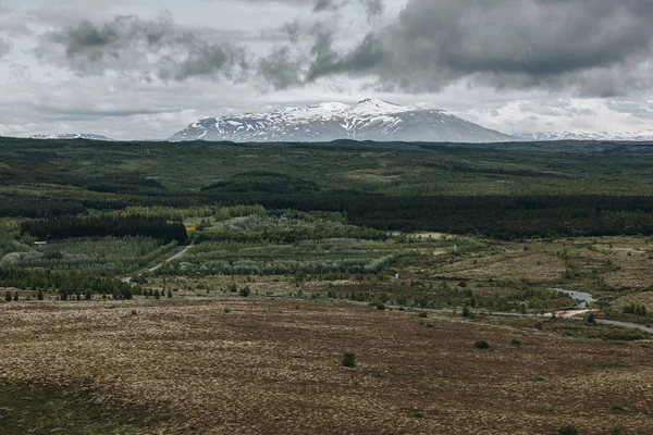 Paysage avec des montagnes couvertes de neige sous un ciel nuageux en Islande — Photo de stock