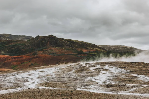 Beau paysage avec des évents volcaniques sous un ciel nuageux dans la vallée de Haukadalur en Islande — Photo de stock