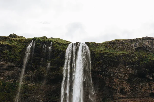 Низкий угол обзора водопада Seljalandsfoss в горных районах Исландии — стоковое фото