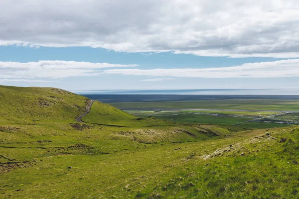 Vue panoramique du paysage avec des hautes terres vertes sous un ciel bleu nuageux en Islande — Photo de stock