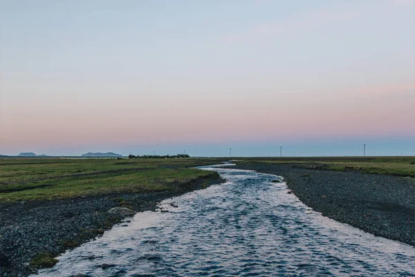 Vista panorámica del paisaje con el río que fluye cerca del prado en Islandia - foto de stock
