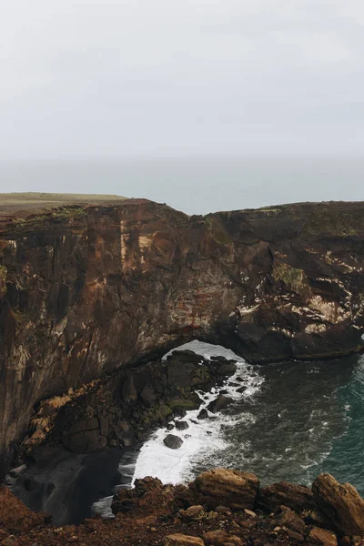 Воздушный вид скалистой скалы и океана под облачным небом на мысе Дырхолай в Вике, Исландия — стоковое фото
