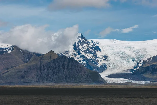 Beau paysage avec des montagnes couvertes de neige sous un ciel nuageux bleu en Islande — Photo de stock