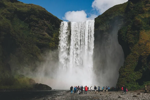 ISLAND - 20. JUNI 2018: Touristen spazieren bei Wasserfall Skogafoss unter strahlend blauem Himmel — Stockfoto
