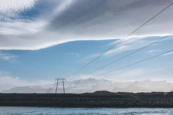 Beautiful icelandic sky above high voltage wires and blue river, Jokulsarlon, Iceland — Stock Photo