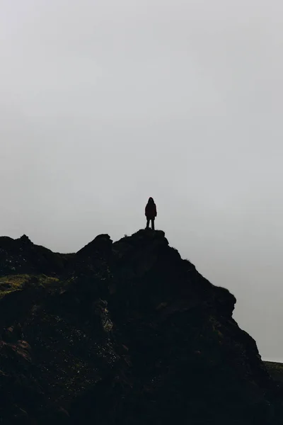 Silhouette di donna in piedi sulla montagna di fronte al cielo nuvoloso — Foto stock