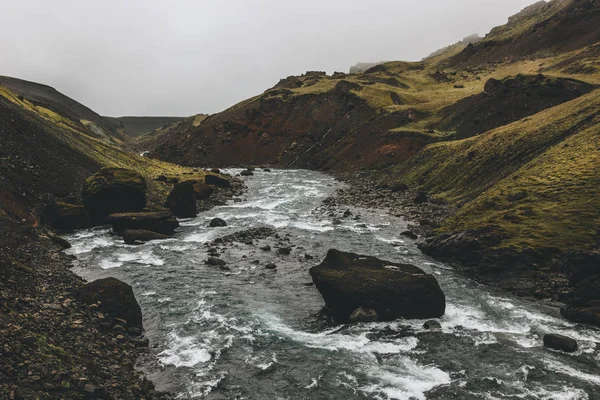 River streaming in green mountains in Iceland on misty day — Stock Photo