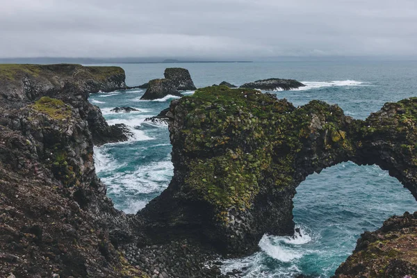 Malerische moosige Klippen vor blauem Meer in Arnarstapi, Island an bewölkten Tagen — Stockfoto