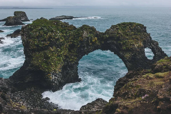 Scogliere muschiose drammatiche di fronte all'oceano blu ad Arnarstapi, Islanda, in una giornata nuvolosa — Foto stock