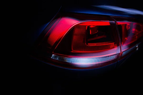 Car rear lights with glossy surface, red backlight of powerful sport sedan bodywork, concept.