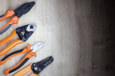 Bir turuncu ve siyah pense, striptizci ve kenar kesici bir ahşap arka plan üzerinde izole dizi.