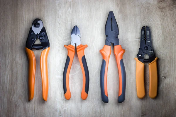 Cutting pliers, gripping pliers, combination pliers, cable cutter. rope cutter and wire stripper. Professional electrician tools on wooden background. Top view.