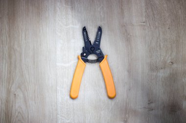 Üstten görünüm tel striptizci aracı. Hafif ahşap arka plan üzerinde izole tel striptizci pense.